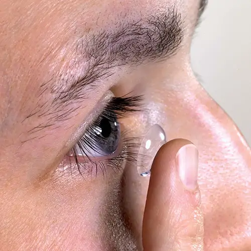 man putting contact lens on his eye