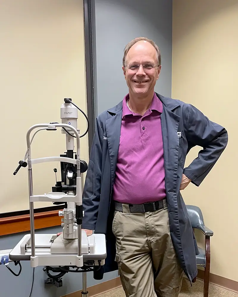 Tom Browning, MD, posing in front of optical exam equipment