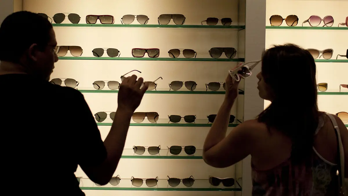2 people trying on sunglasses and trying to pick out a pair